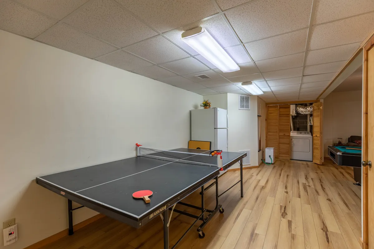 A playful interior scene with a ping pong table, refrigerator, and laundry area, set up for friendly matches and socializing. The relaxed atmosphere makes it easy to imagine impromptu game nights and gatherings with friends.