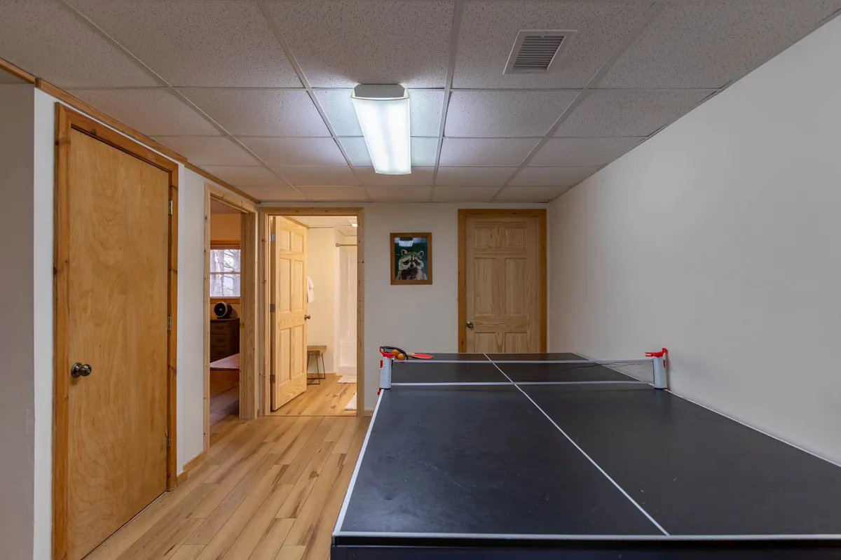 A ping-pong table set up in a wood-accented room, complemented by rustic doors and framed artwork on the wall. The area is well-lit and arranged for friendly matches and socializing, highlighting the recreational vibe.